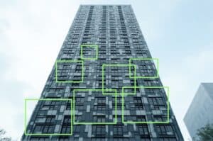 a highrise building with a facade that tricks a.i. into detecting faces that aren't there. Green bounding boxes show the false positive predictions of the a.i.